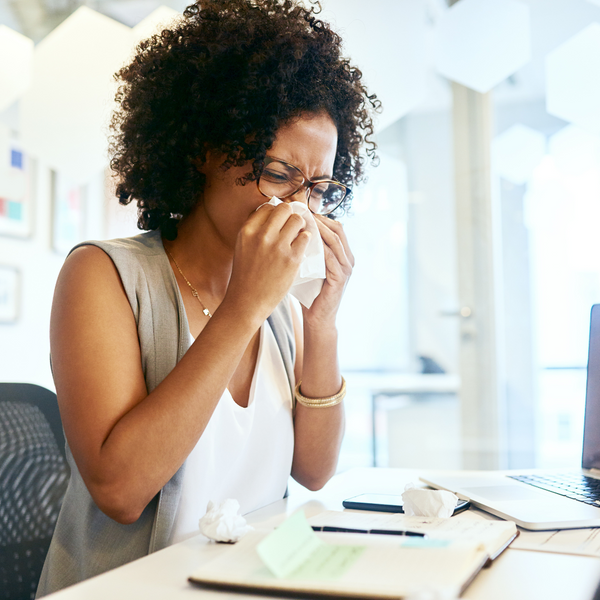 Woman office employee blowing nose into tissue