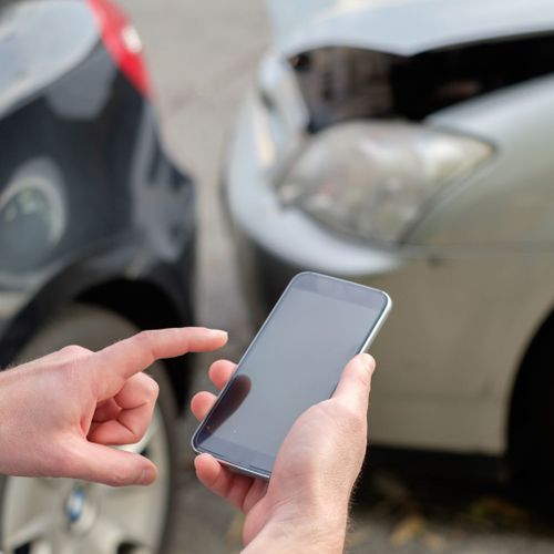 person holding phone to call insurance company after car accident person holding phone to call insurance company after car accident