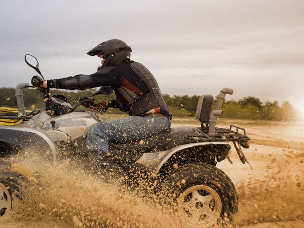 man riding an atv through mud and sand man riding an atv through mud and sand