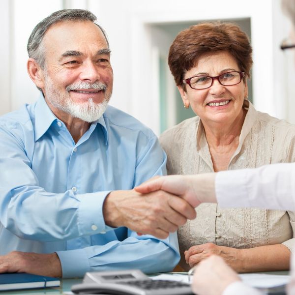 older couple shaking hands with insurance agent