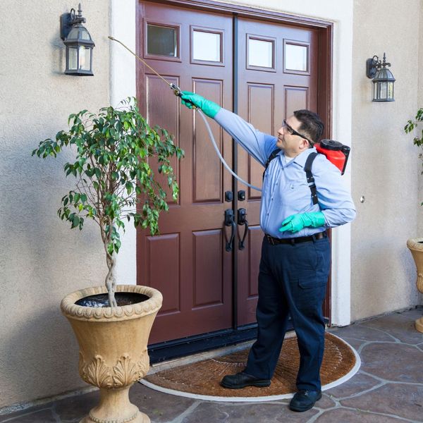 a pest control worker spraying around a door