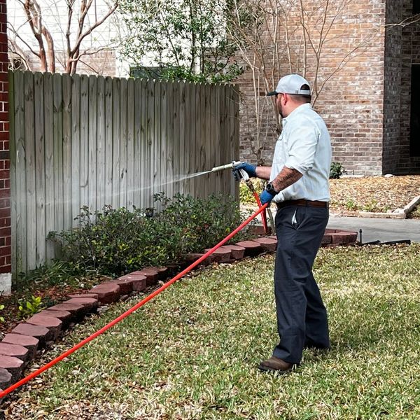 A BugPro professional spraying a backyard.
