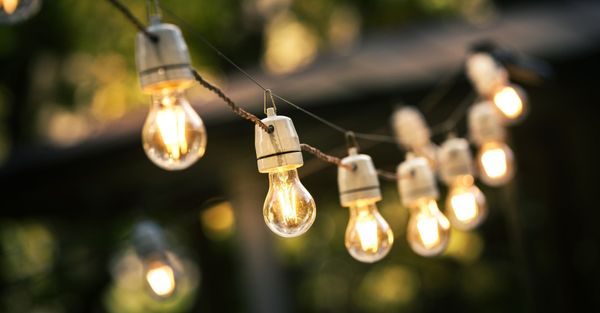A string of warm, glowing filament light bulbs hanging outdoors, creating an inviting evening ambiance. A string of warm, glowing filament light bulbs hanging outdoors, creating an inviting evening ambiance.