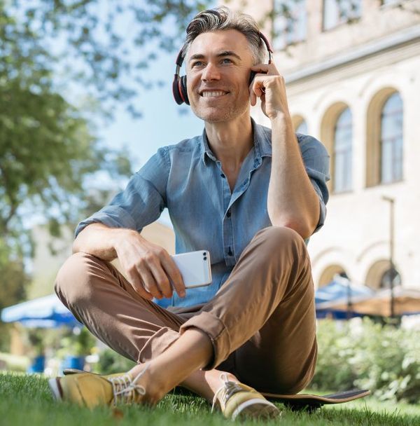 A man sitting on a skateboard in the grass 