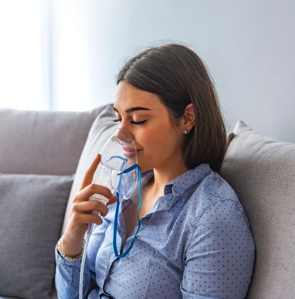 A woman putting on a nebulizer mask