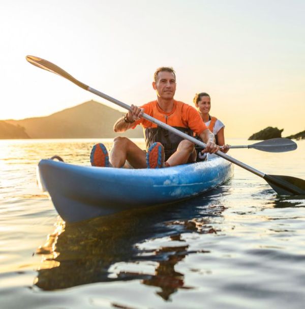 A man and woman in a kayak during a sunset