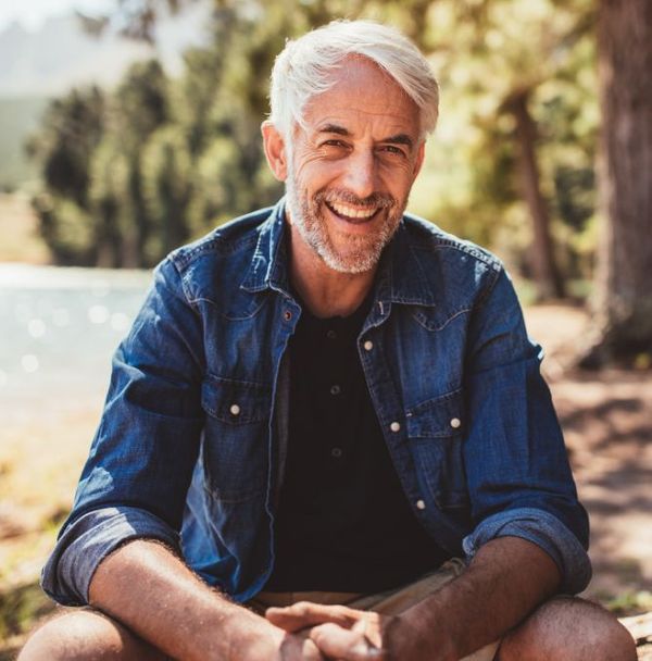 A portrait of an older man smiling in the forest