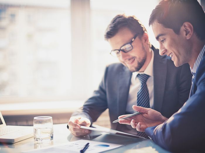  Two businessmen discussing and reviewing financial and business graphs.