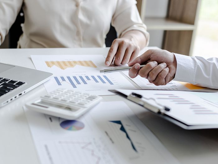  Two businessmen smile while reviewing documents and reports.