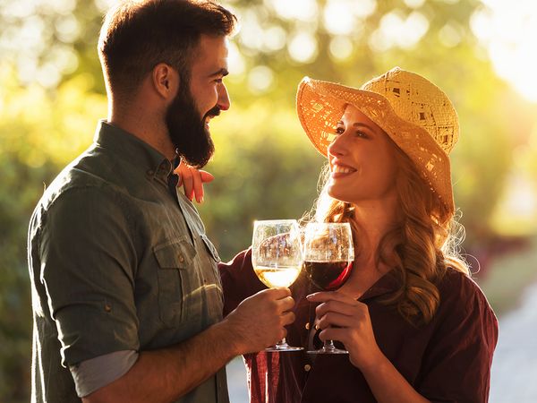 Man and a woman on a wine tour, clinking their glasses together.