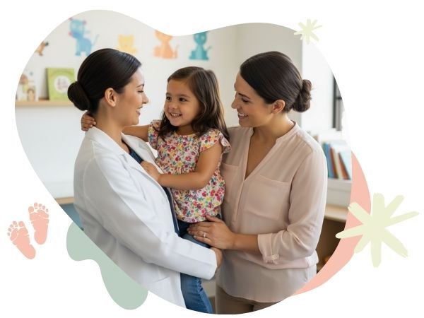 a pediatrician holds a small girl as she and her mother smile