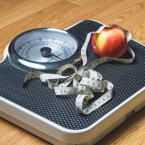 Scale with a tape measure and an apple on it. 