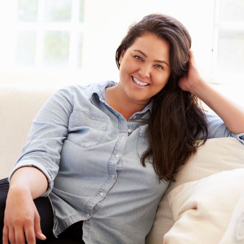 Woman sitting on a couch, smiling. 