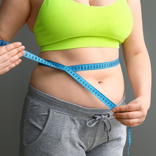 Woman measuring her waist with a tape measure. 