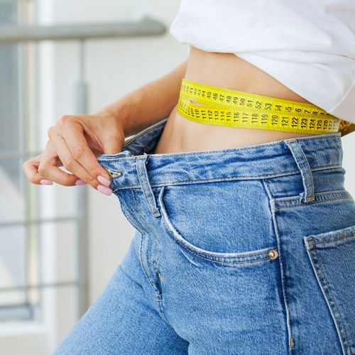 woman in jeans taking her waist size