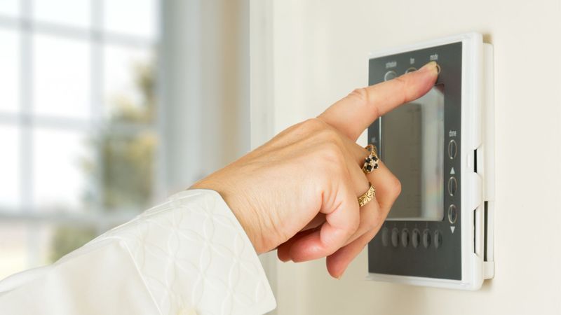 a woman adjusting a thermostat The Top Reasons Your Furnace Needs Professional Repair This Winter Hero.jpg