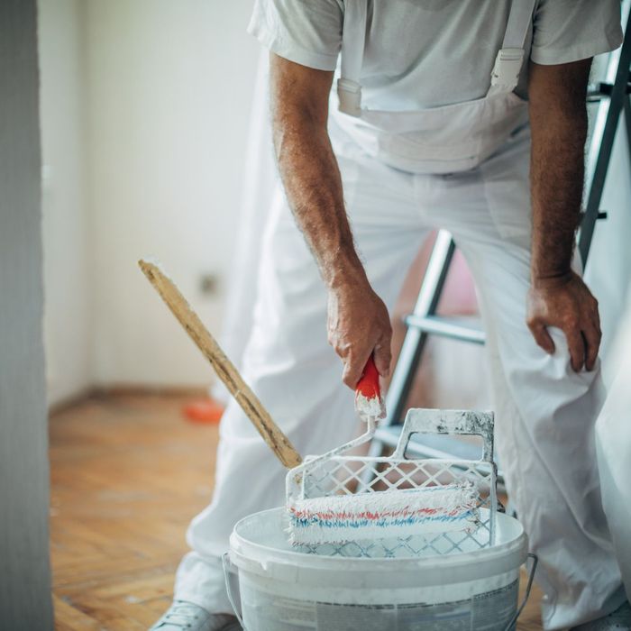 A painter dipping a brush into paint