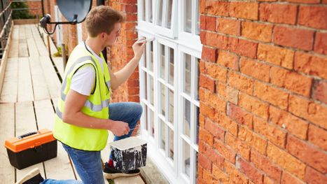 Man paints the exterior shutters of a home