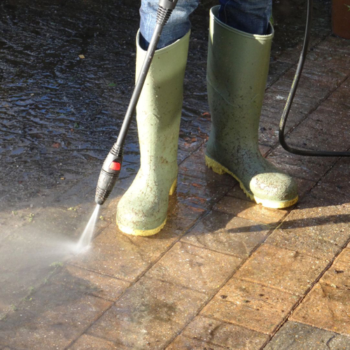 Person pressure washing a stone walkway. 