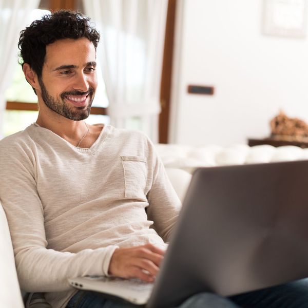 Person smiling while using a laptop