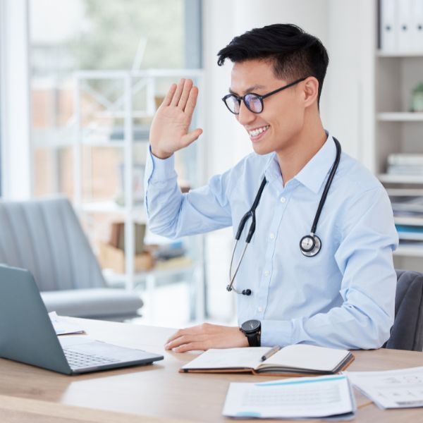 A doctor waving while on a video call