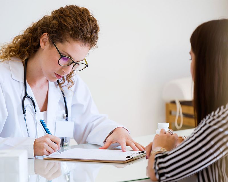 Female doctor reviewing clipboard paperwork with patient