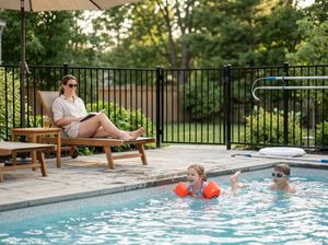 Family relaxing by backyard swimming pool