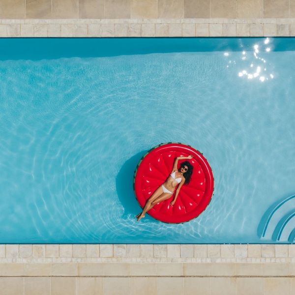 woman laying on a red floaty in a blue pool