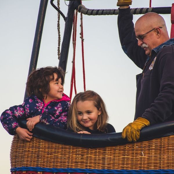 two young girls and a man in a hot air balloon