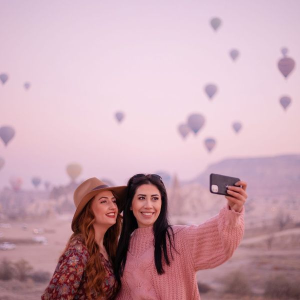 two friends taking a selfie with hot air balloons