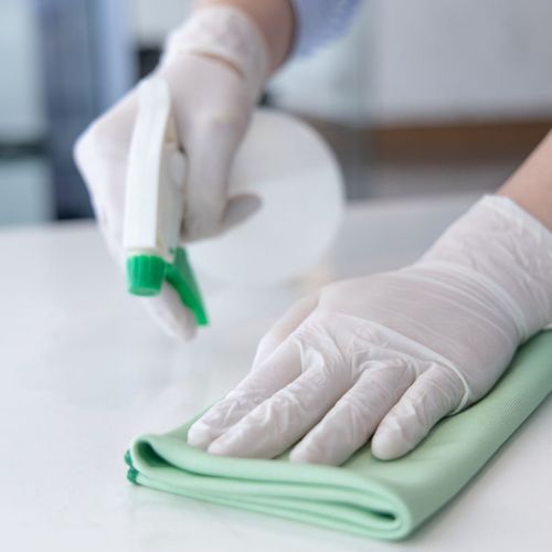 Person sprays and wipes white countertop