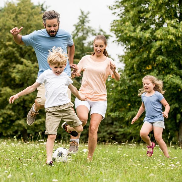 man playing soccer with his family