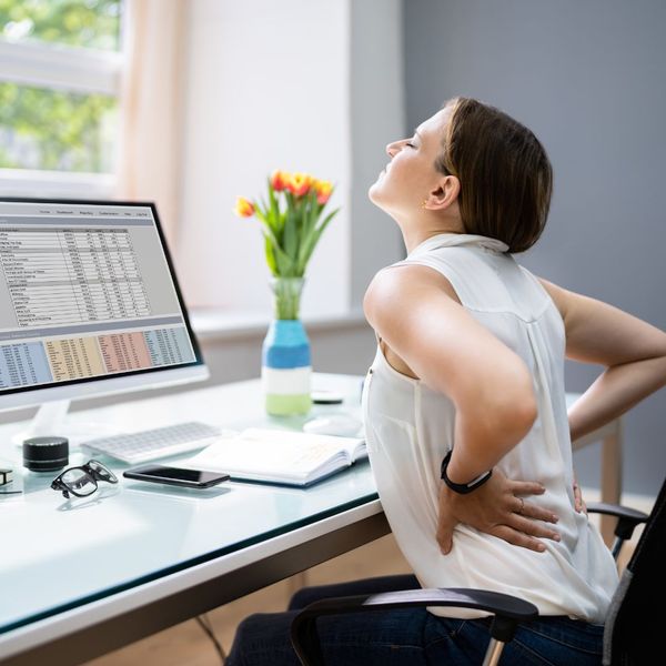 Lady at her desk holding her back in pain