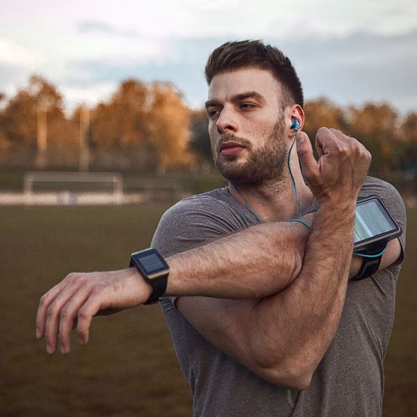 a man listening to music and doing an arm stretch