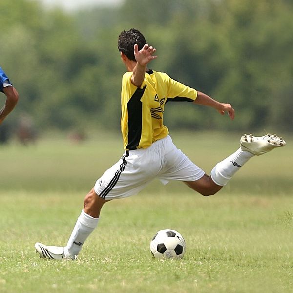 a soccer player wearing soccer gear and kicking a ball