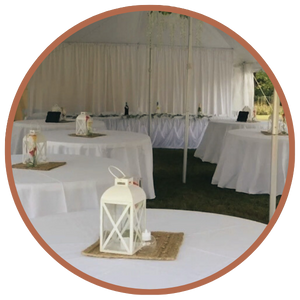 Tables covered by white linens at wedding, beneath tent
