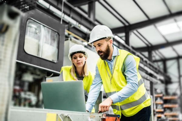 employees in hard hats looking at a computer