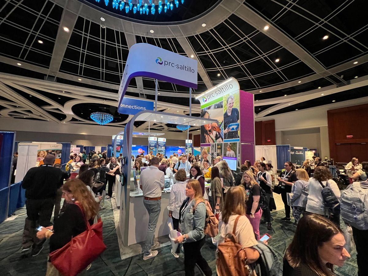 Busy trade show booth uses overhead branding and graphics for visibiilty 