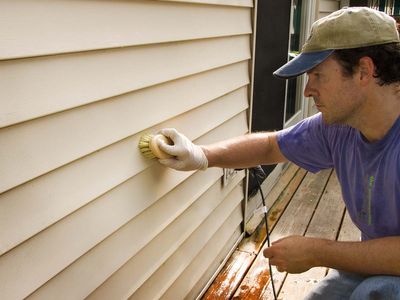 Maintenance gently cleaning the siding on a home.