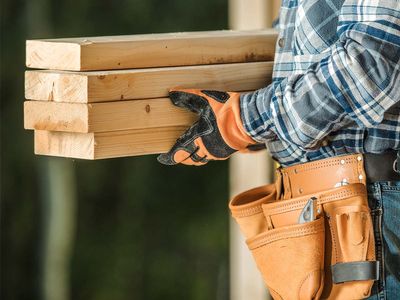 Closeup of construction worker carrying wooden beams for renovation.