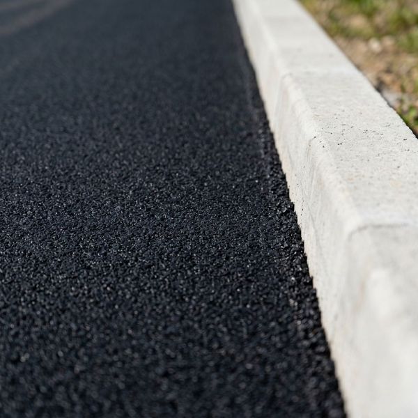 Close-up of smooth, high-quality black asphalt paving showing professional texture and precision edge work.