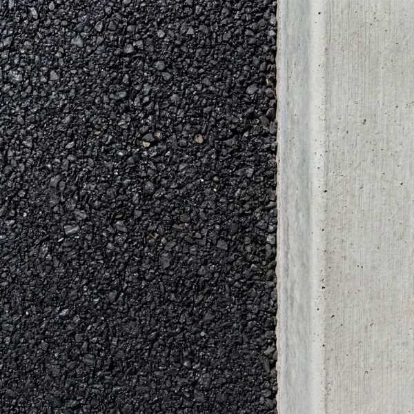 Close-up of the smooth, uniform texture and clean edges of a professional asphalt paving job.