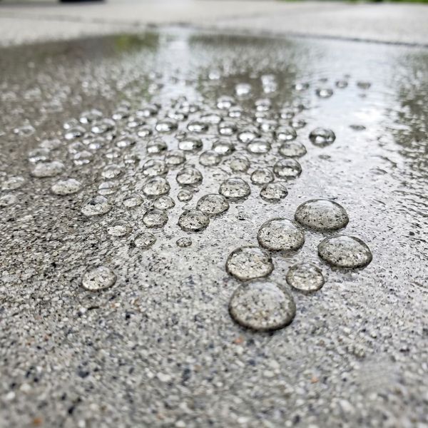 Close-up of a sealed concrete patio showing water beading on the protected surface.