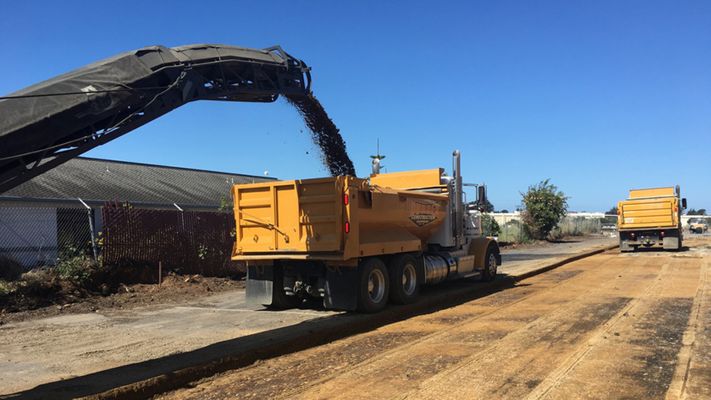 Durden Construction dump truck receiving recycled asphalt from a milling machine during paving preparation. Durden Construction dump truck receiving recycled asphalt from a milling machine during paving preparation.