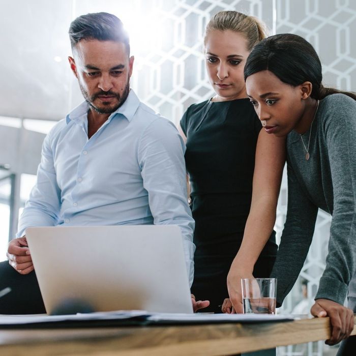 group of professionals gathered around a laptop