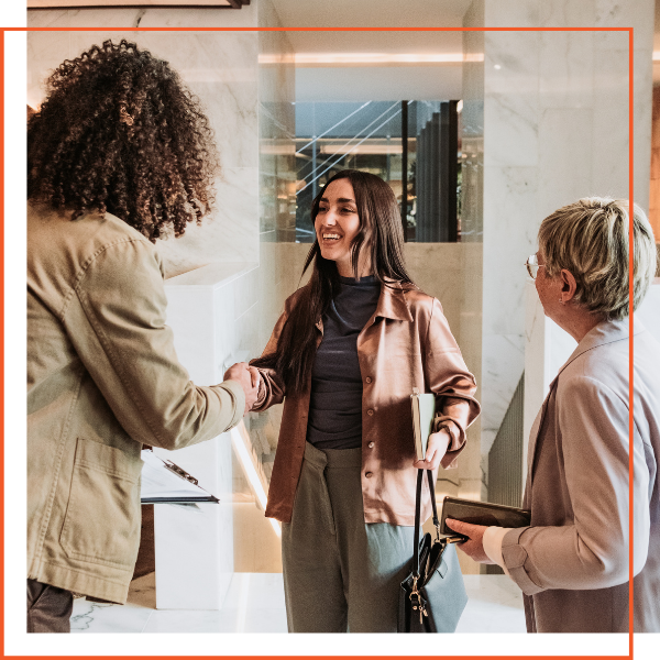 Woman shaking hands with 2 other women Woman shaking hands with 2 other women