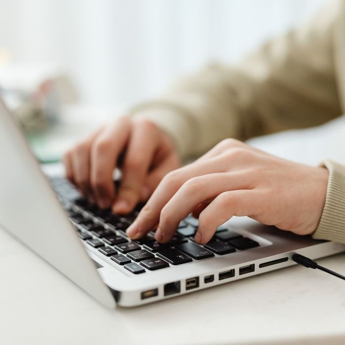 A close-up view of hands typing quickly on a silver laptop keyboard, emphasizing high-intensity productivity and deep focus.