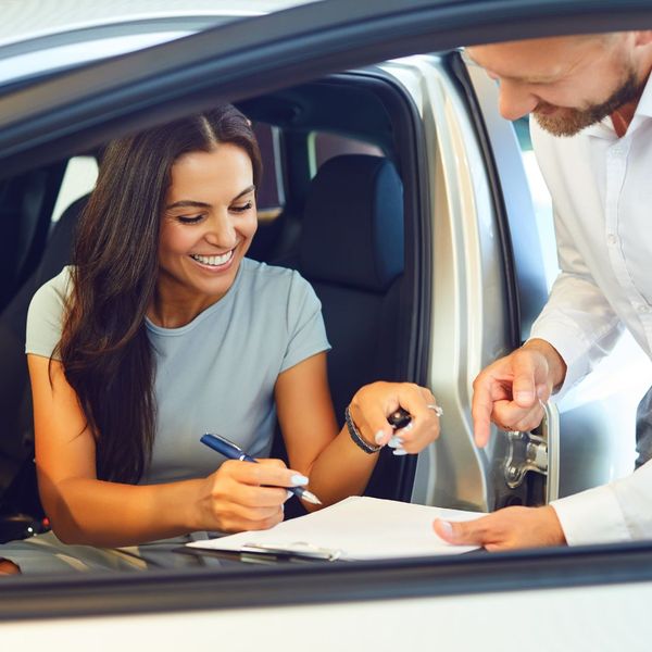 woman signing paperwork at car dealership