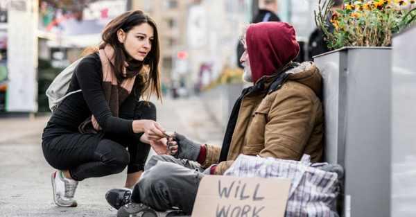 image of a woman giving money to a homeless man