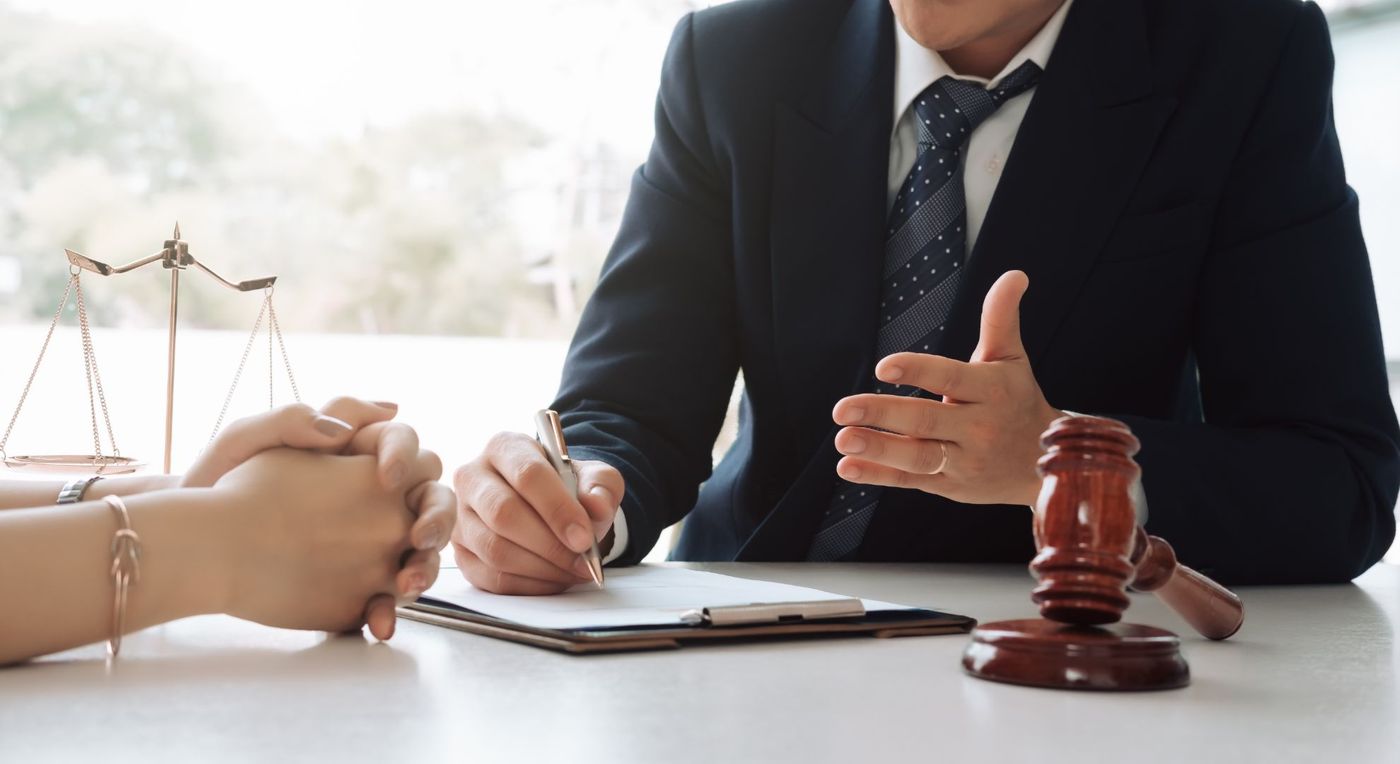 attorney talking to client, gavel and scales on desk